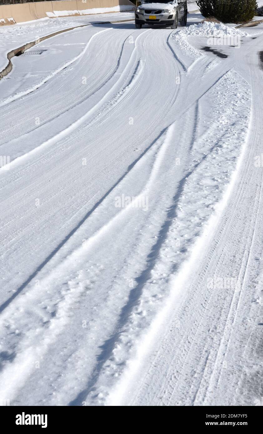 Autoreifenspuren auf einer schneebedeckten Straße in Santa Fe, New Mexico. Stockfoto