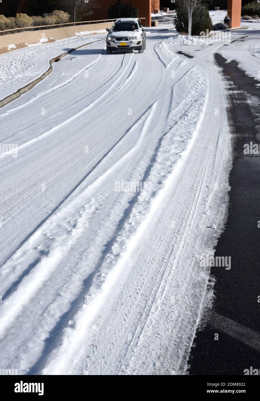Eine Autofahrerin fährt ihr Auto auf einer schneebedeckten Straße in Sasnta Fe, New Mexico. Stockfoto