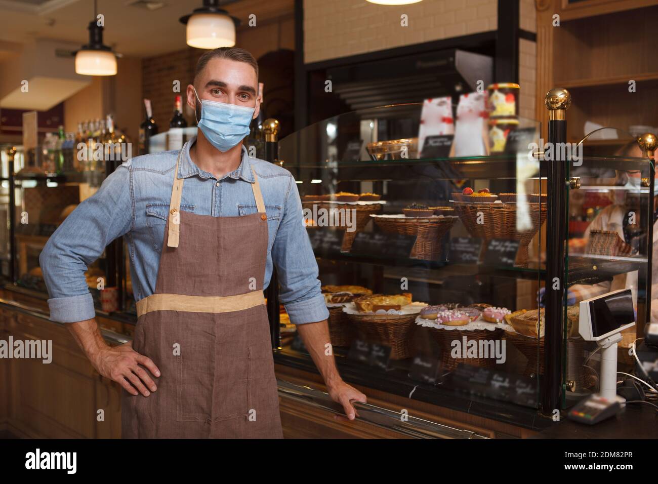 Männlicher Bäcker trägt medizinische Gesichtsmaske arbeitet in seiner Bäckerei Während der Quarantäne des Coronavirus aufbewahren Stockfoto