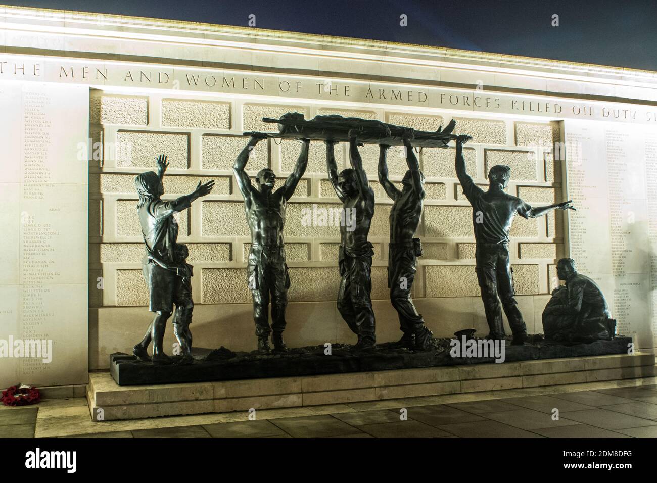 'The Stretcher Bearers' Denkmal im National Arboretum, Großbritannien. Eine Frau trauert um ihren Verlust, während seine Kameraden ihn nachts in die Höhe tragen Stockfoto