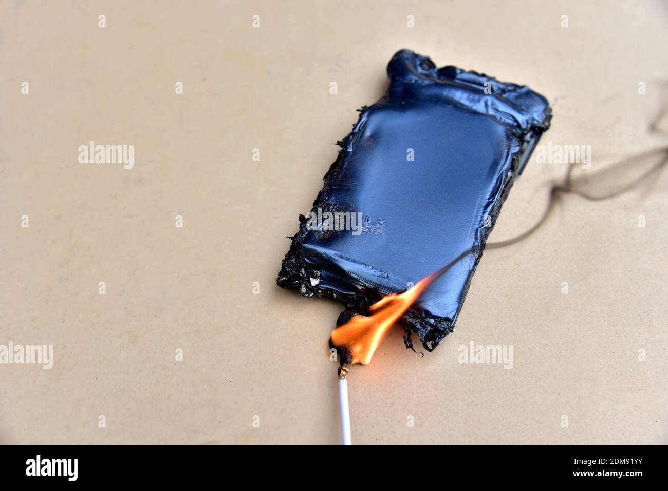 Mobiltelefon hat Feuer aus dem Kabel mit dem Aufladen aus dem elektrischen Netz in der Steckdose gefangen. Kostengünstige Ladegeräte gefährden Ihre Zelle. Kabel o Stockfoto