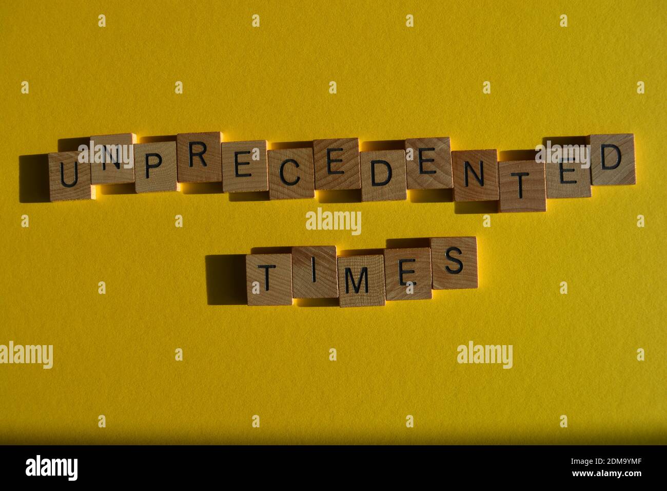 Unprecented Times, phrase in wooden alphabet letters isolated on yellow background Stockfoto