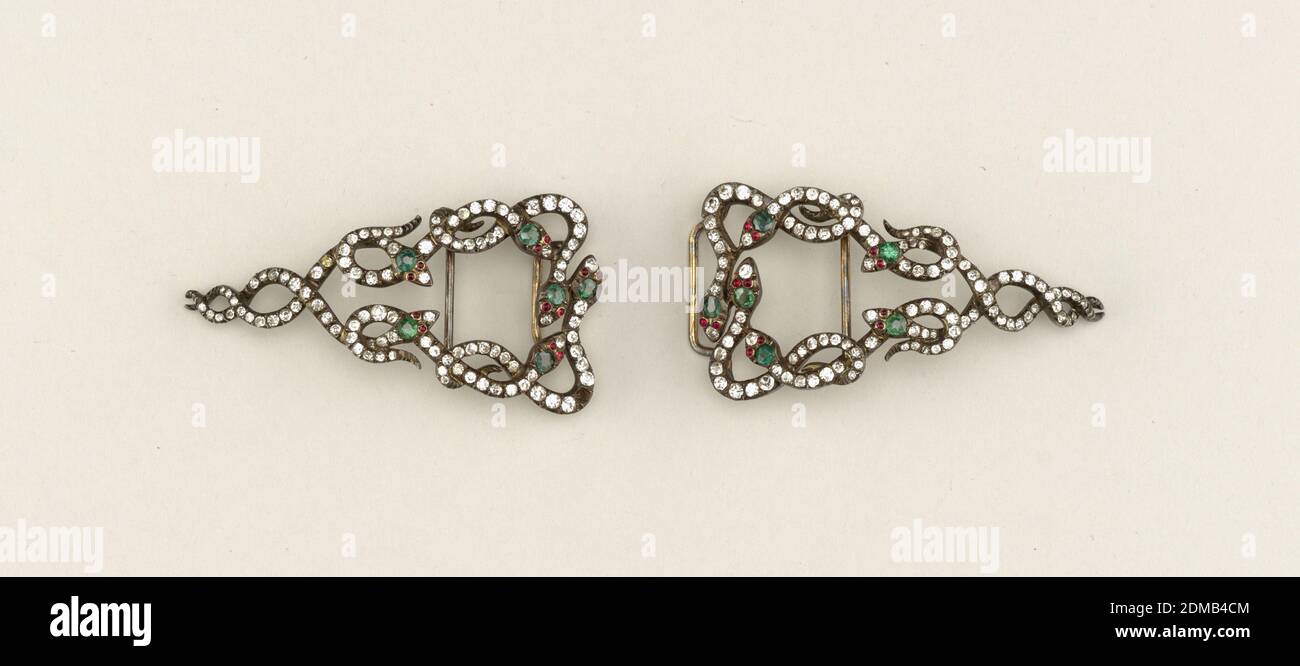 Schlangenform Gürtelschnalle, Silber vergoldet, Glas, Schnalle in zwei Teilen: Jeder Teil ist dreieckig und besteht aus verschlenkten Schlangenschnecken (sechs Schlangen in jedem Teil); Körper mit eingestickten Diamantenpaste, Köpfe, mit Smaragd- und Rubinpaste. Schnalle ist auf einem Polster aus weißem Satin montiert, ein Stein fehlt., Frankreich, ca. 1890, Schmuck, Dekorative Künste, Schnalle, Schnalle Stockfoto