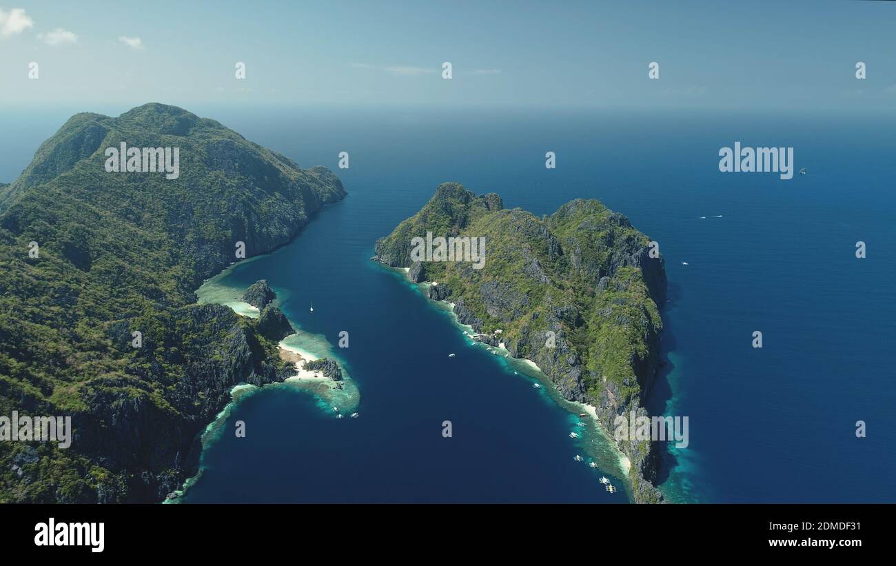El Nido-Inseln bei blauer Meeresbucht Luftaufnahme. Grüne Berginsel mit tropischem Wald am Sandstrand. Wunderbare Seeslandschaft mit grünen Inseln des philippinischen Archipels. Drohnenaufnahme im Kino Stockfoto