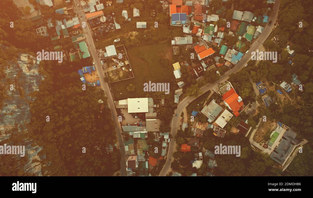 Top down Zeitlupe Luftbild Stadtlandschaft mit Lodges, Häuser, Gebäude Dächer und Straßen in grünen tropischen Wald. Epische urbane Landschaft des Palawan Resorts im Sommer. Filmische Drone mit sanftem Sonnenlicht von oben nach unten Stockfoto