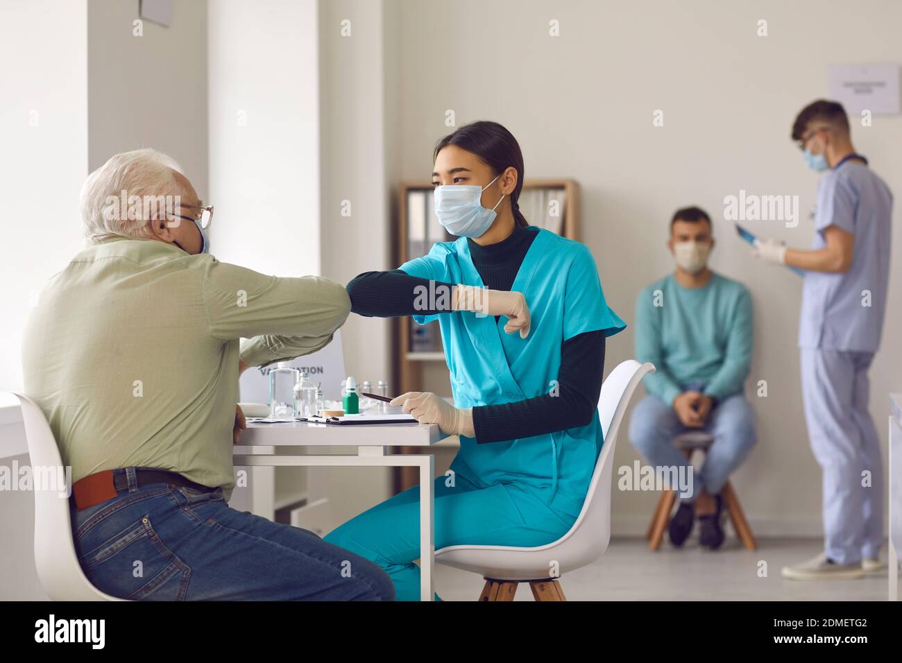 Junge Krankenschwester im Gesicht Maske stoßen Ellbogen mit älteren Mann Vor der Verabreichung des Impfstoffs Stockfoto