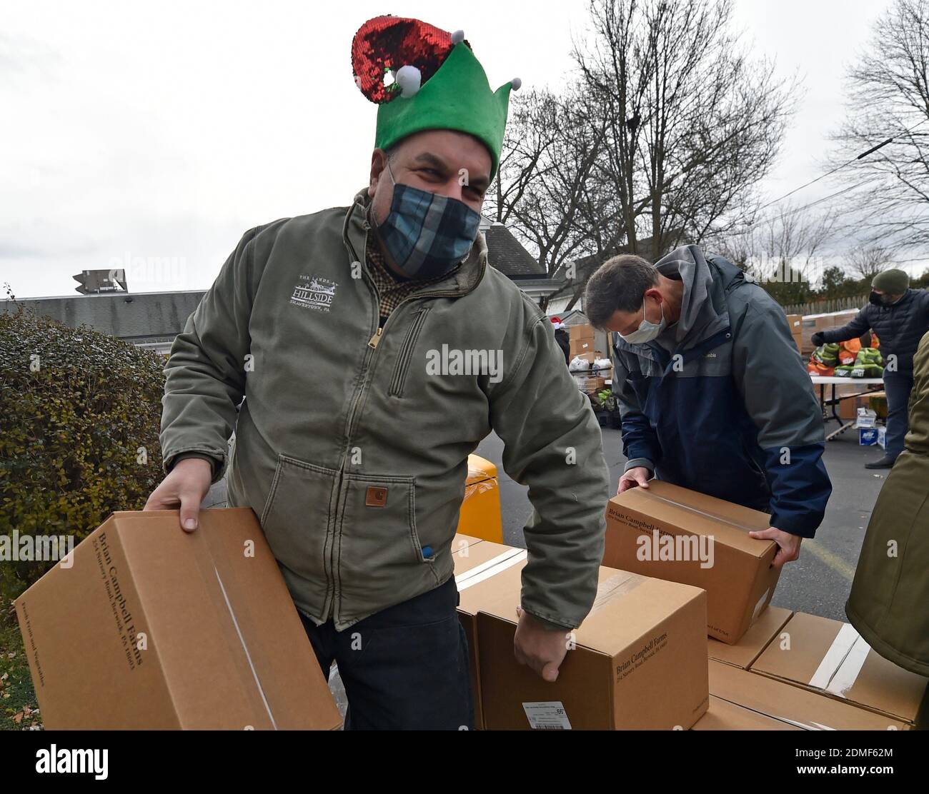 Kingston, Usa. Dezember 2020. Ein Freiwilliger trägt Kisten mit Produkten zu einem Auto an der Lebensmittelbank.seit dem Start von Covid ist die Al Beech Speisekammer sehr beschäftigt, heute haben sie dort einen Millionsten Gast bedient. Für Weihnachten trugen Freiwillige Weihnachtsmützen und verteilten Geschenkkarten, Süßigkeiten und Luftballons zusammen mit den regulären Lebensmitteln. Kredit: SOPA Images Limited/Alamy Live Nachrichten Stockfoto