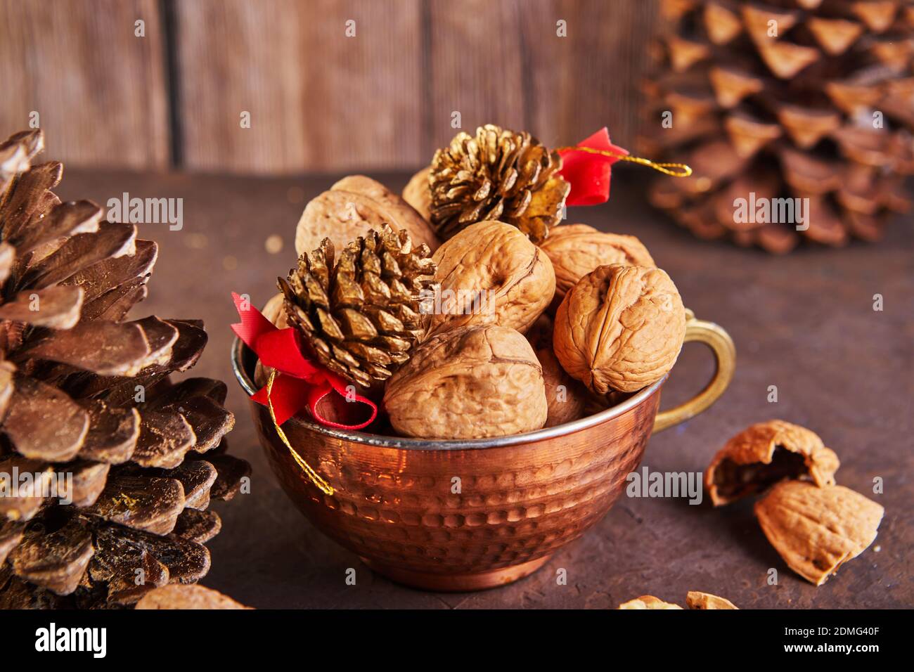Walnüsse in einem Blechbecher, ganz und gehackt, neben der Füllung und Schalen. Präsentiert in einer Neujahrskomposition mit Tannenzapfen. Home Lagerung des Winters Stockfoto