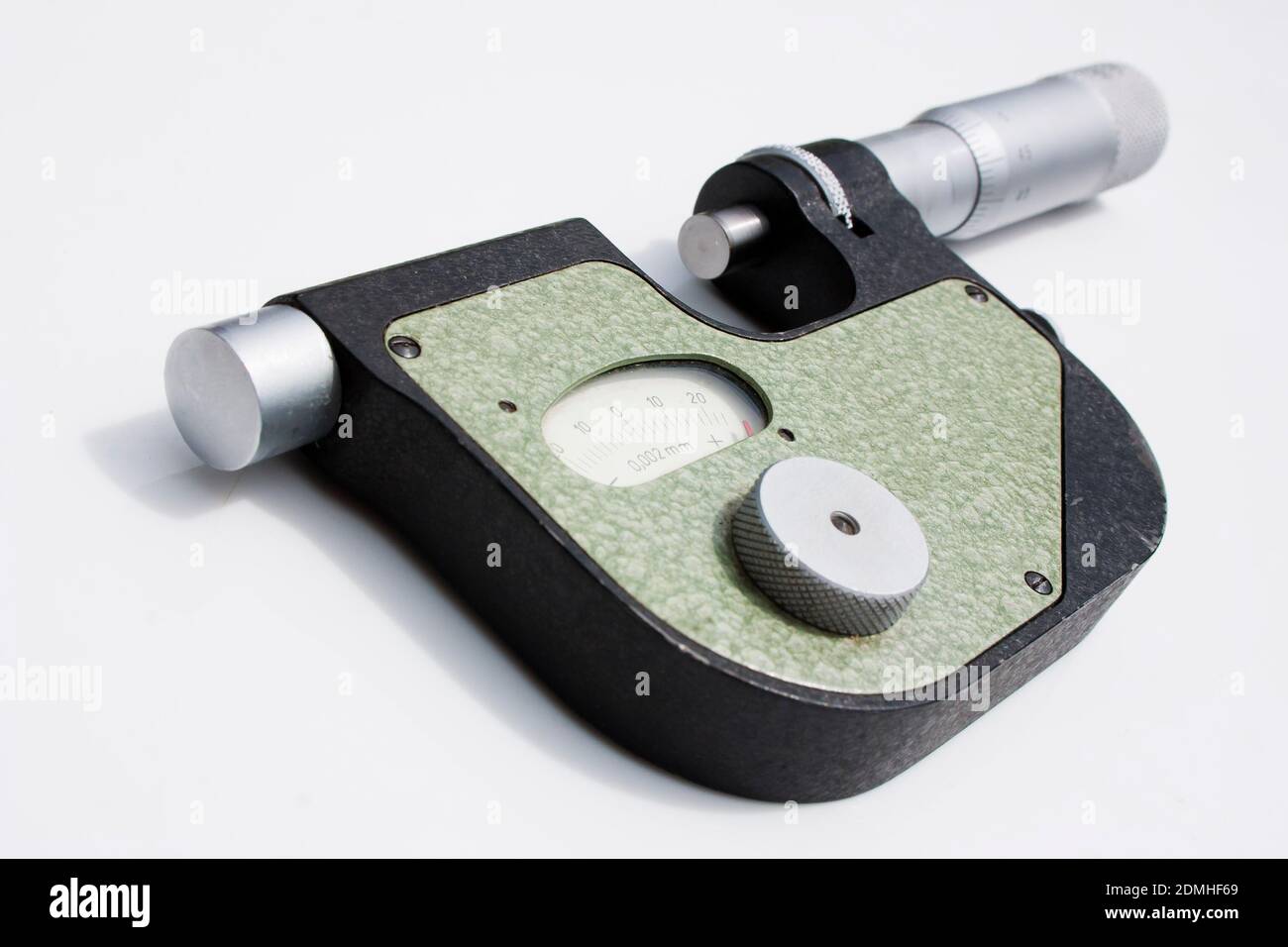 Dies ist ein Mikrometer. Präzises Messgerät - Mikrometer- oder Indikatorhalterung liegt auf einer weißen Oberfläche Stockfoto