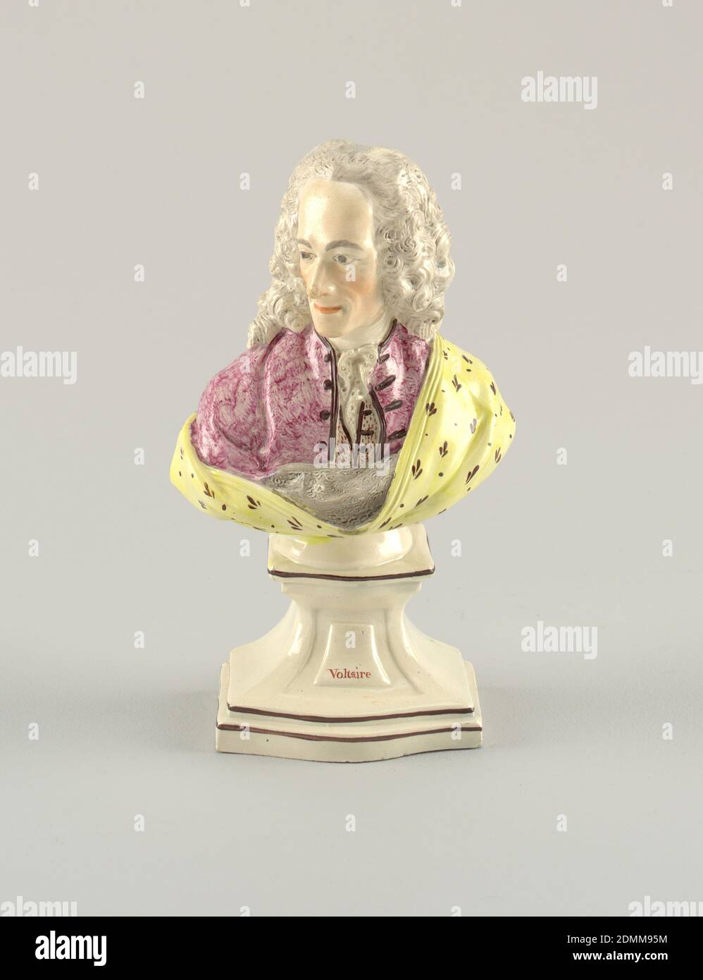 Voltaire, Glasiertes und emailliertes Steingut, auf elfenbeinfarbenem Keramiksockel mit dem Namen 'Voltaire', ist Büste von Voltaire in langer Perücke mit leicht nach rechts gedrehtem Kopf. Er trägt einen Rosenmantel offen, um rosa gepunktete Weste und weißen Kravettenenden zu zeigen. Um die Figur herum und die linke Schulter bedeckt ist ein grau-liniertes gelbes Tuch mit kleinem braunen Muster., England, Ende des 18. Jahrhunderts, Keramik, Dekorative Kunst, Büste, Büste Stockfoto