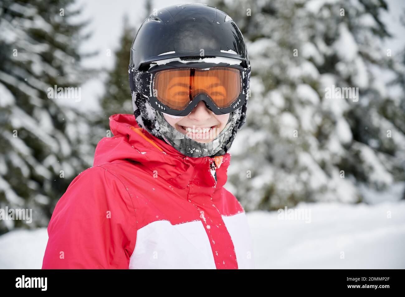 Porträt eines lächelnden Mädchen trägt rote Jacke, Helm und Brille in verschneiten Bergen, Nahaufnahme. Konzept der Winter Arten von Sport Stockfoto
