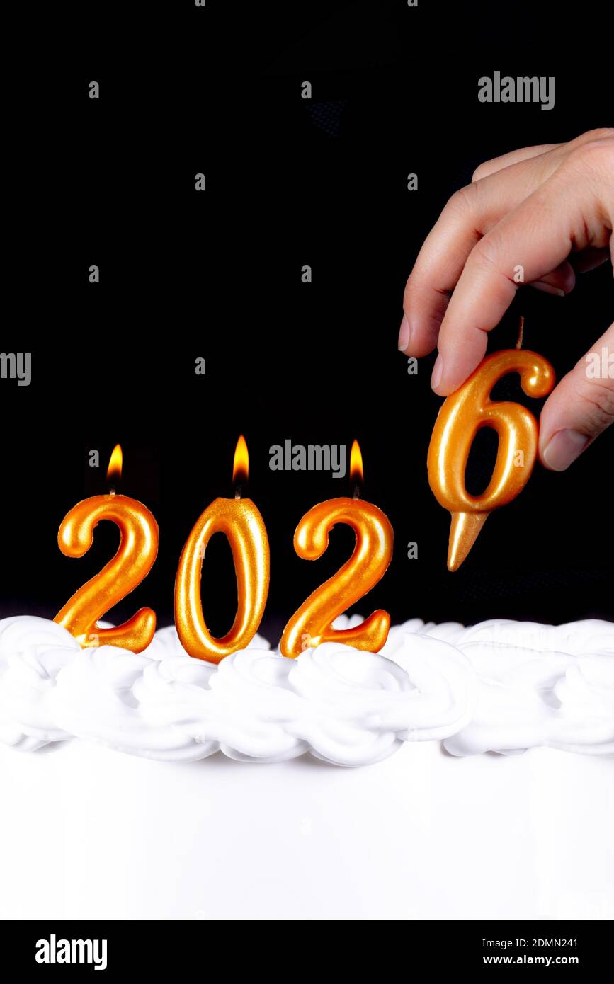 Vier goldene Kerzen schreiben Zahlen Flamme glückliches neues Jahr 2026 Hand schwarzer Hintergrund Stockfoto