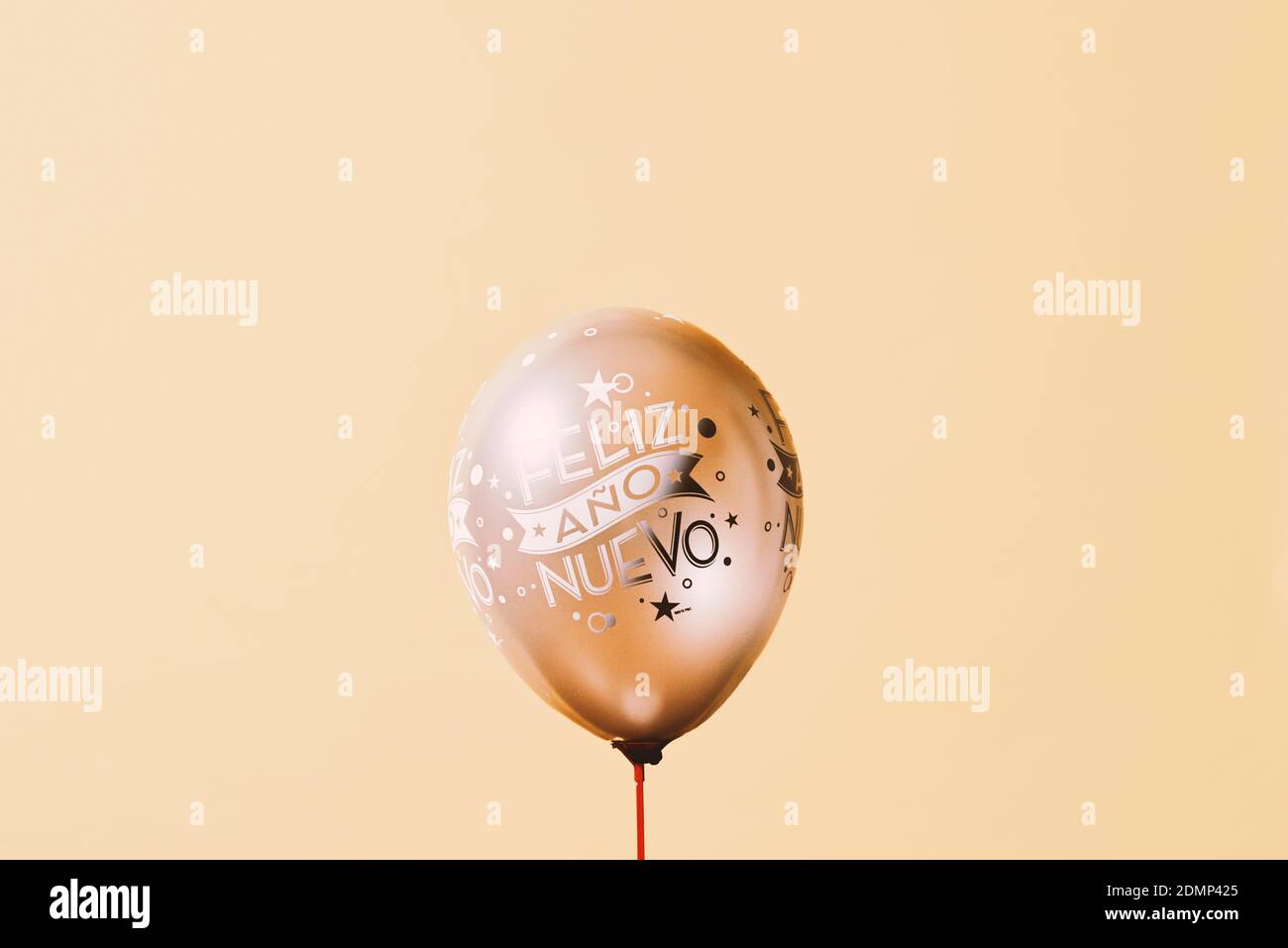 Ein goldener Ballon mit dem Text glückliches neues Jahr in spanisch geschrieben, vor einem beigen Hintergrund mit etwas Leerzeichen um ihn herum Stockfoto