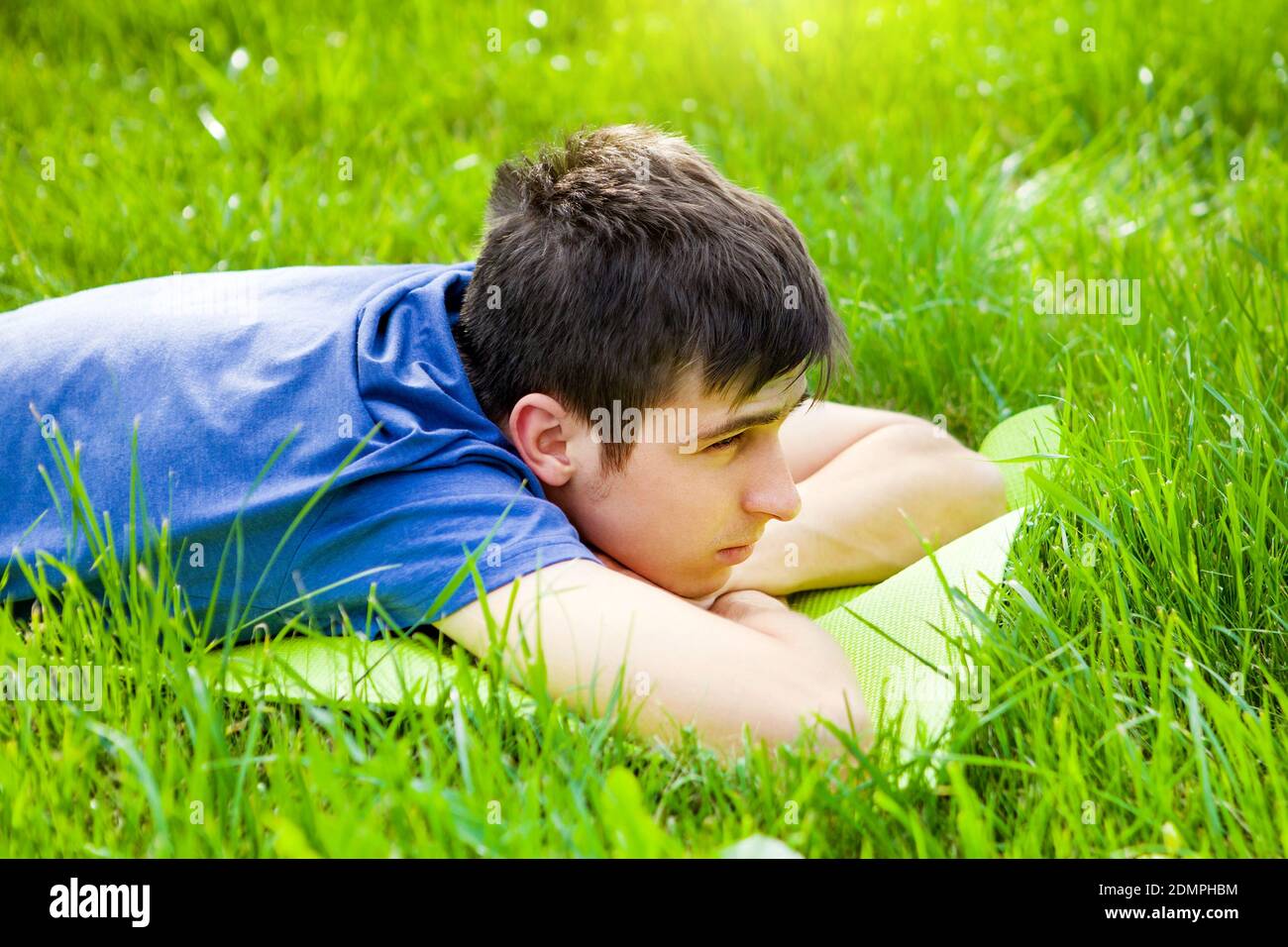 Nachdenklicher junger Mann auf dem Gras der Sommerwiese Stockfoto