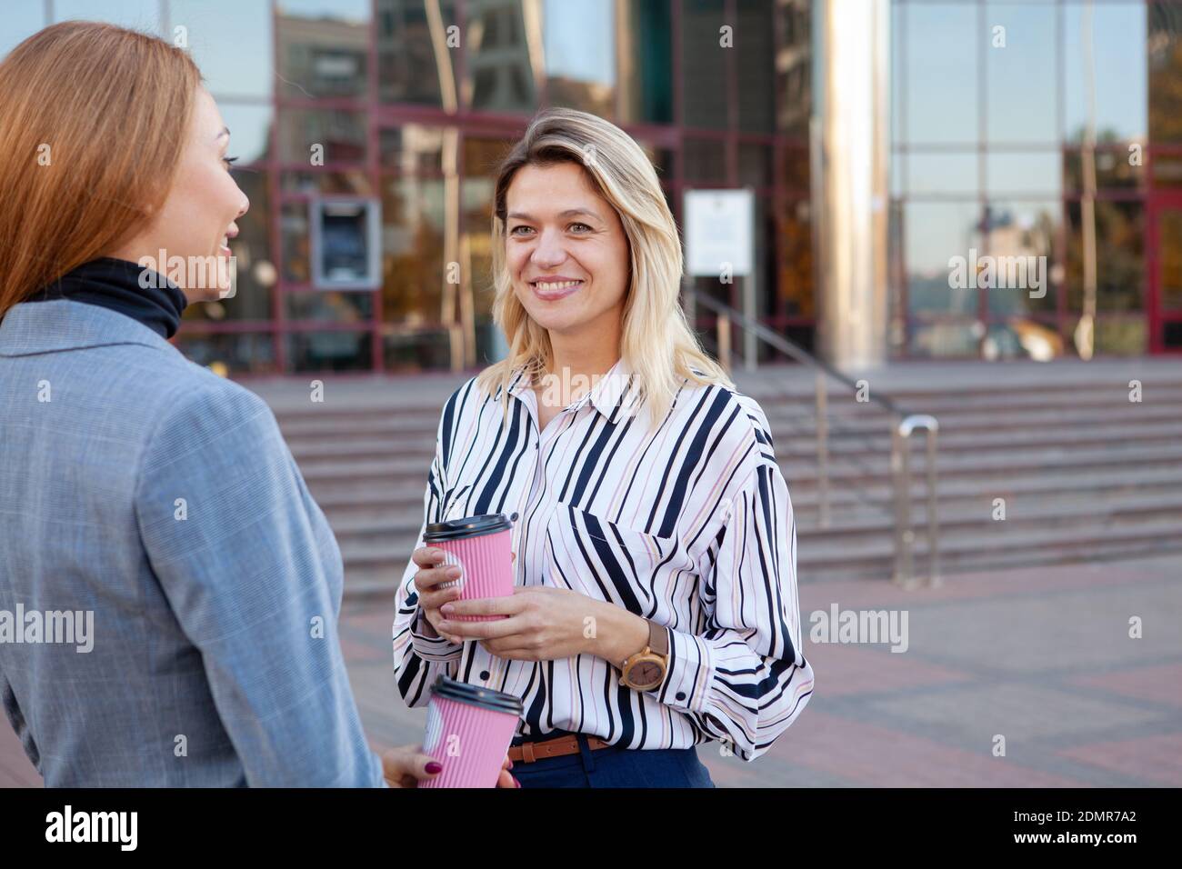 Reife Geschäftsfrau mit Kaffee mit ihrem Kollegen im Freien. Zwei Unternehmerinnen mit Kaffeepause während des Arbeitstages Stockfoto