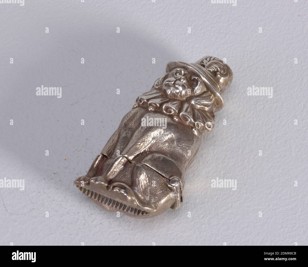 Hund in Federhut und Rüschenhalsband, Silber, in Form eines sitzenden Hundes mit Rüschenkragen und Federhut, auf Band auf der Rückseite des Hutes 'Rd.1465' eingeschrieben (?- unleserlicher Eindruck). Deckel öffnet sich unten, Scharnier an der Seite über dem Schwanz. Stürmer versenkt in Boden., Ende des 19. Jahrhunderts, Container, Dekorative Kunst, Matchsafe, Matchsafe Stockfoto