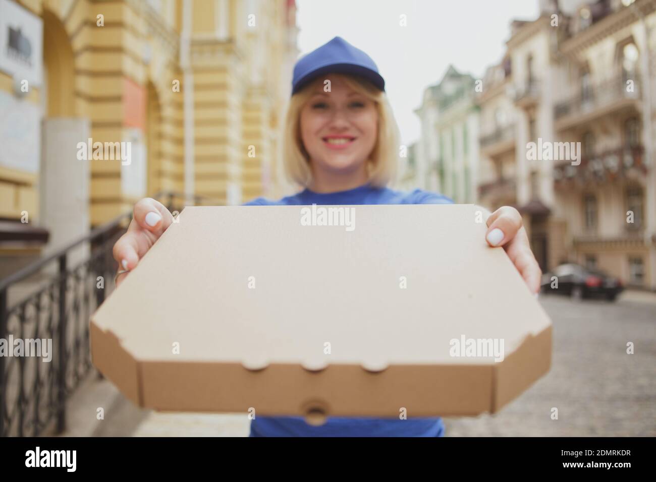 Glückliche weibliche Lieferung Kurier lächelnd, halten aus Karton Pizza-Box an die Kamera, kopieren Raum. Fröhliche Pizza Lieferung Frau mit Karton-Box wi Stockfoto