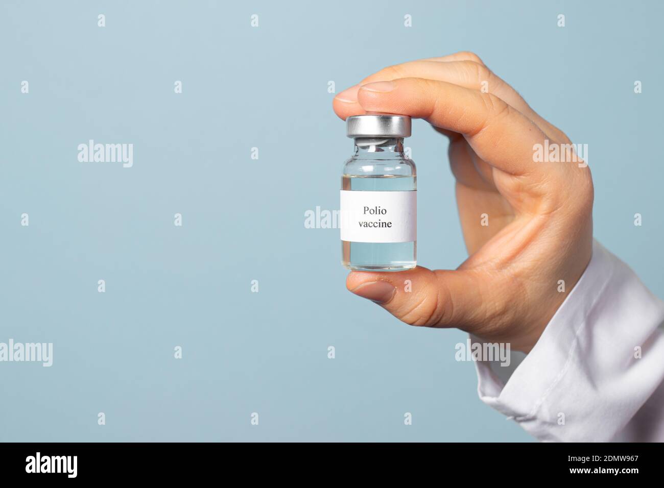 Ein Arzt oder Labortechniker hält einen Polio-Impfstoff auf blauem Hintergrund. Impfung und Prävention Poliomyelitis. Kindliche Lähmung Stockfoto