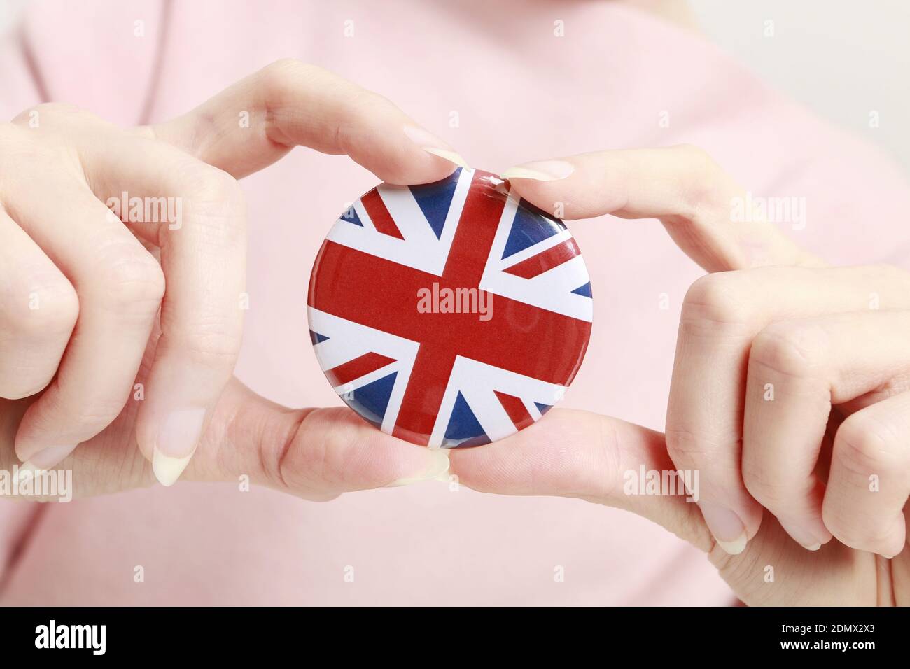 Die Flagge von Großbritannien, allgemein bekannt als Union Jack auf Knopf Abzeichen gedruckt, hält von Frau in ihrer schönen Hand. Stockfoto