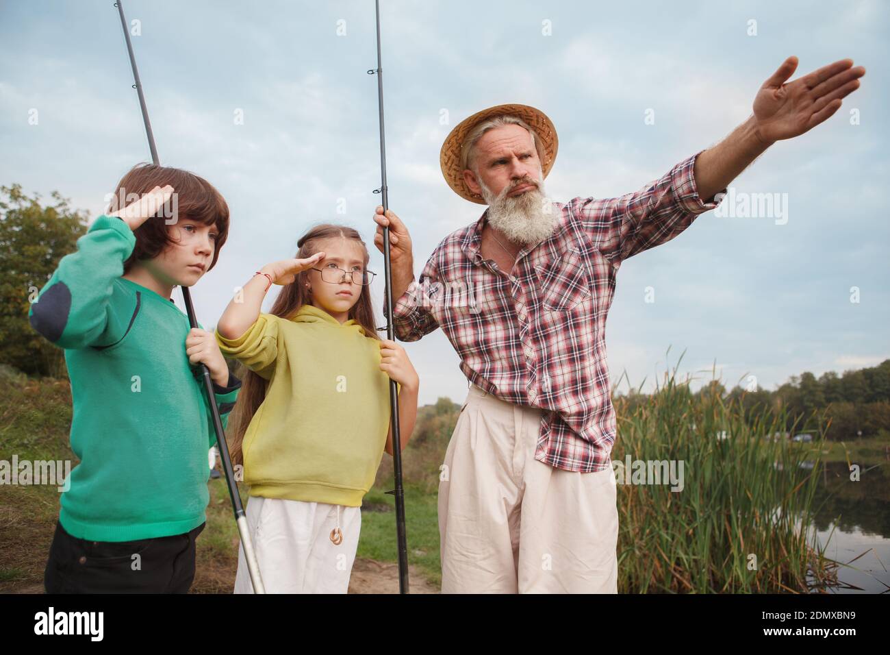 Senior Mann lehrt seine Enkel über das Angeln, suchen streng und ernst Stockfoto