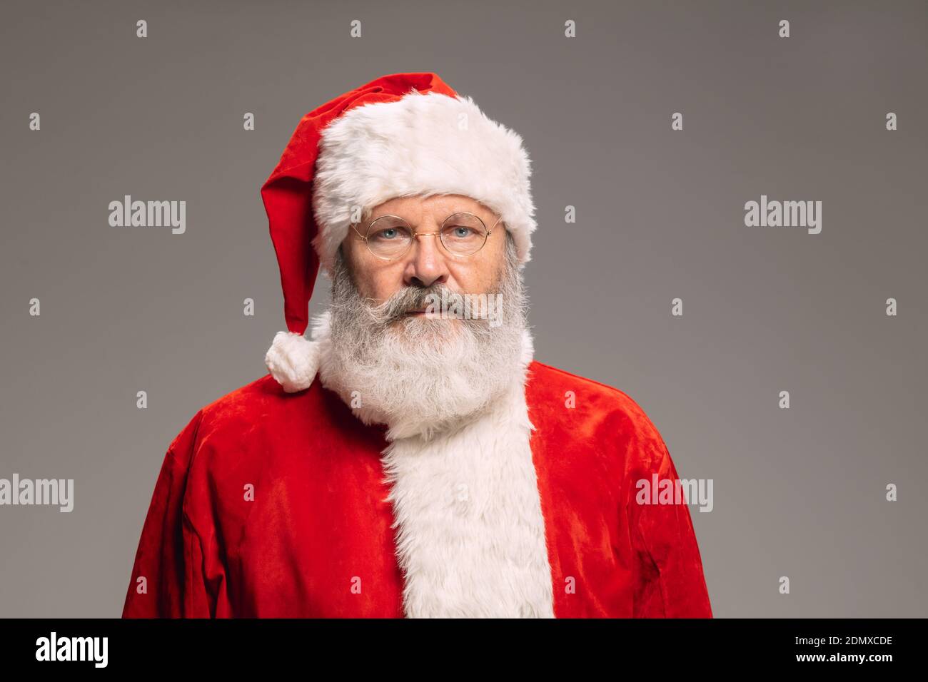 Senior Mann wie Santa Claus isoliert auf grauen Studio-Hintergrund. Kaukasischer bärtiger Mann Modell in traditioneller Tracht. Neujahr 2021, Geschenke, Feiertage, Winterstimmung. Copyspace für Ihre Anzeige. Kater Stockfoto