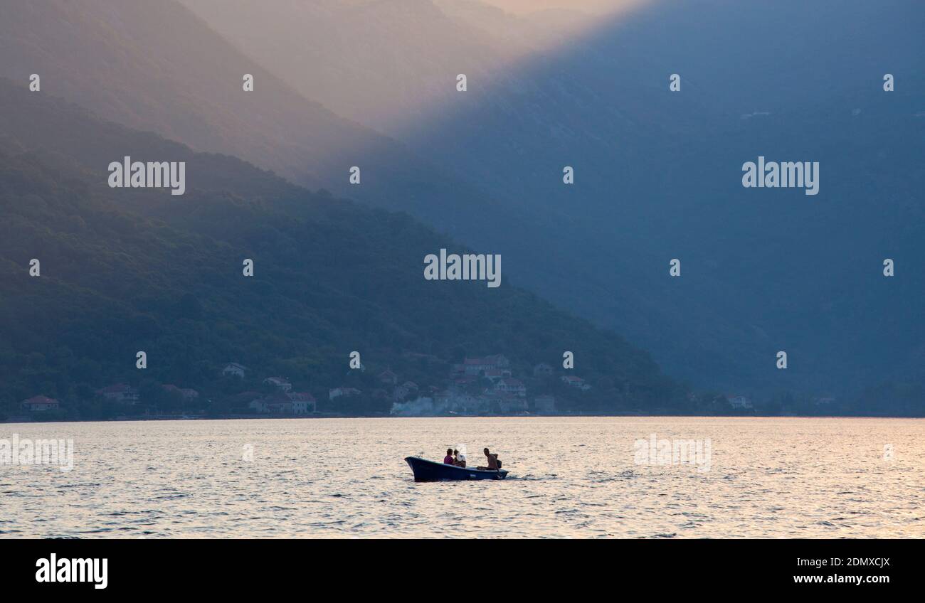 Perast, Kotor, Montenegro. Blick über die Bucht von Kotor, Abend, kleines Boot von hohen Berglandschaft Zwerg. Stockfoto
