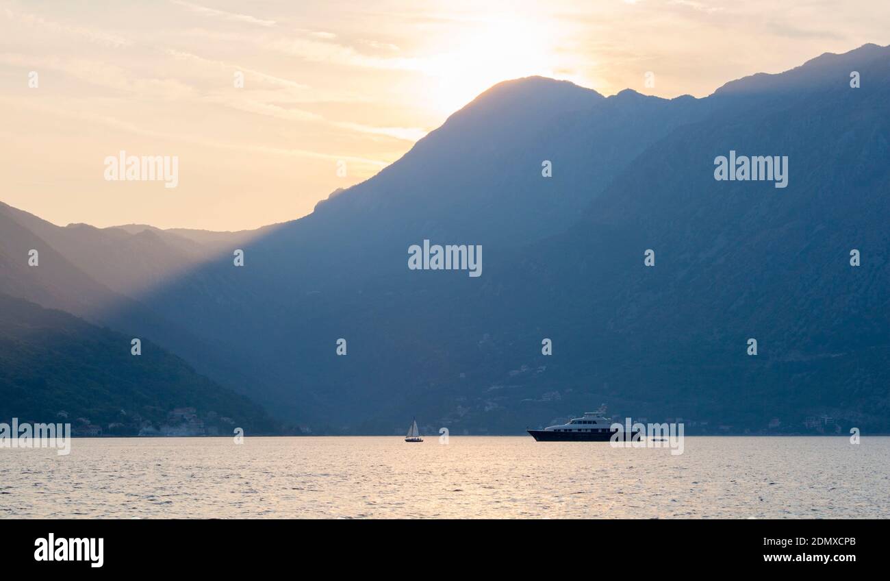 Perast, Kotor, Montenegro. Blick über die Bucht von Kotor, Abend, Sonnenstrahlen werfen dunkle Schatten auf hohe Berglandschaft. Stockfoto
