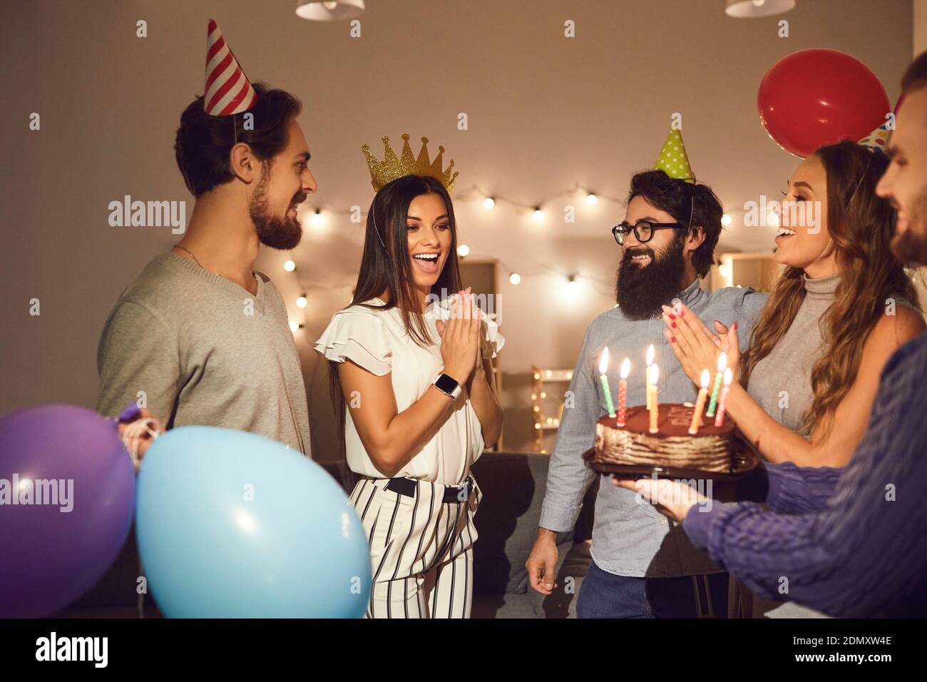 Gruppe von Freunden wünschen alles gute zum Geburtstag der jungen Frau und Geben ihr Geburtstagstorte Stockfoto