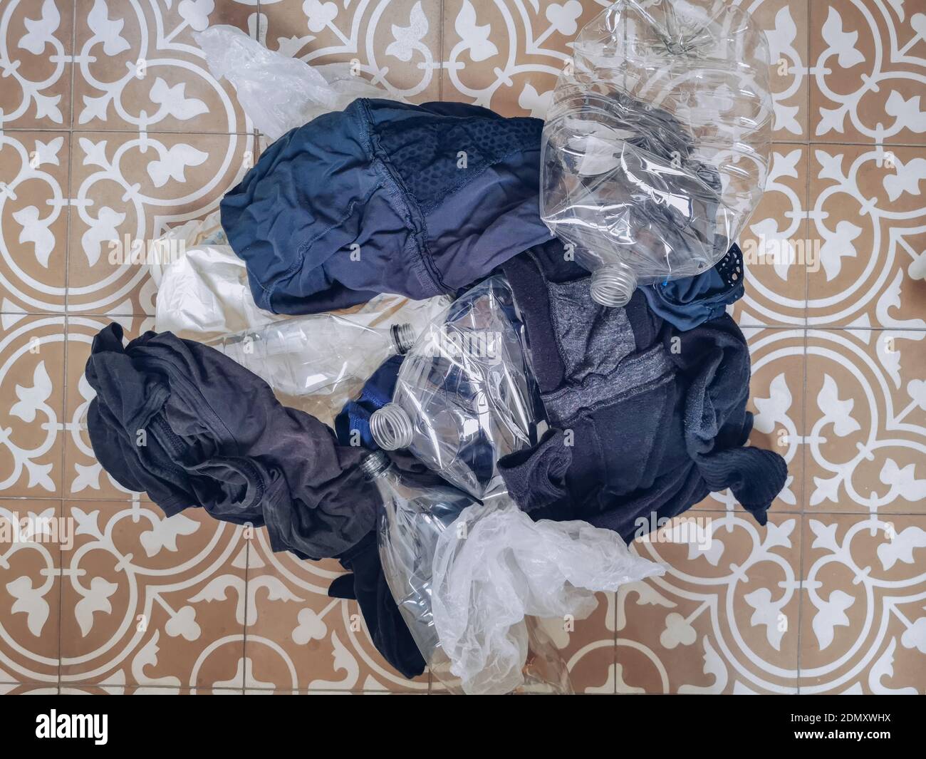 Stapel von Kleidung und Kunststoffabfällen, die Mikrokunststoffabfälle darstellen Verschmutzung bei der Wäsche Stockfoto