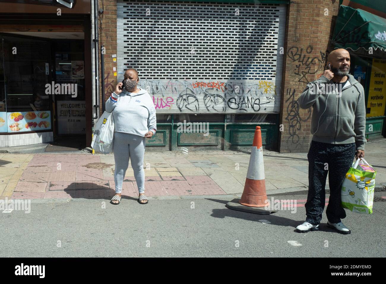 Zwei Menschen auf ihren Telefonen tragen Masken Stockfoto