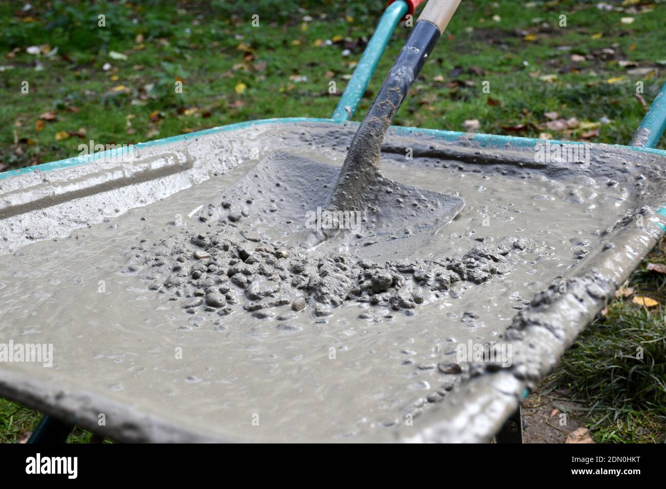 Schubkarre voller Beton und genagelte Metall- und Holzschaufel. Stockfoto