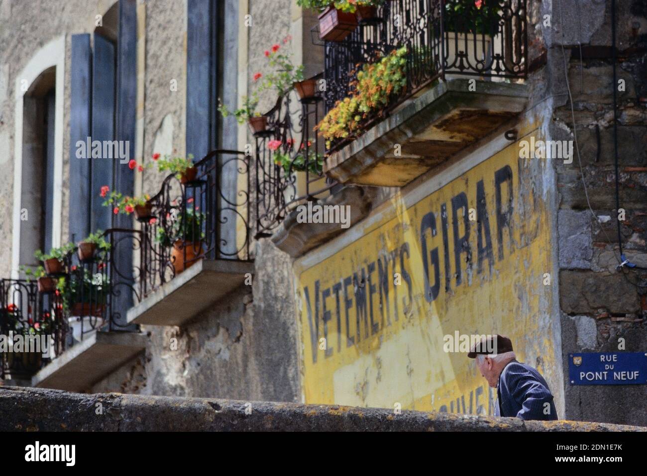 Der alte Franzose in einer Baskenmütze ging an einer alten bemalten Werbung, Limoux, vorbei. Languedoc Südfrankreich. Europa Stockfoto