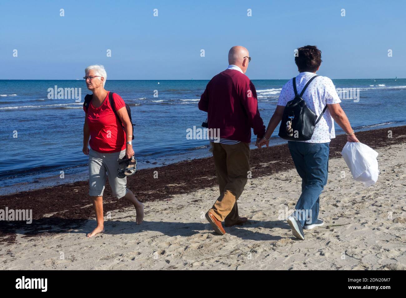 Ältere Paare, die zusammen am Strand spazieren Stockfoto