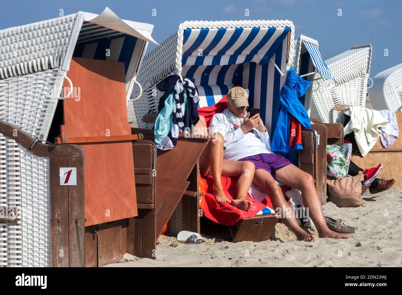 Menschen genießen einen sonnigen Tag, geschützt vom Wind durch Liegestühle, Warnemunde Strand Rostock Deutschland Sommerurlaub Sommertag Stockfoto