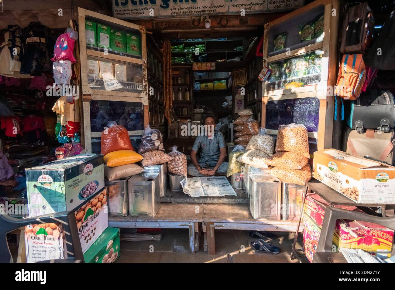 Jamnagar, Gujarat, Indien - Dezember 2018: Ein indischer Ladenbesitzer sitzt in seinem Lebensmittelgeschäft in den Marktstraßen der Stadt. Stockfoto