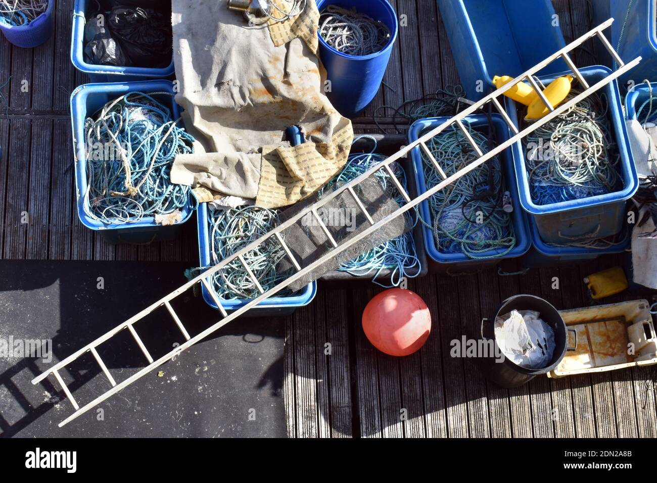 Blick von oben auf die Angelausrüstung mit Leiter und Fischernetzen, die auf einem Holzdock im Hafen organisiert sind Stockfoto