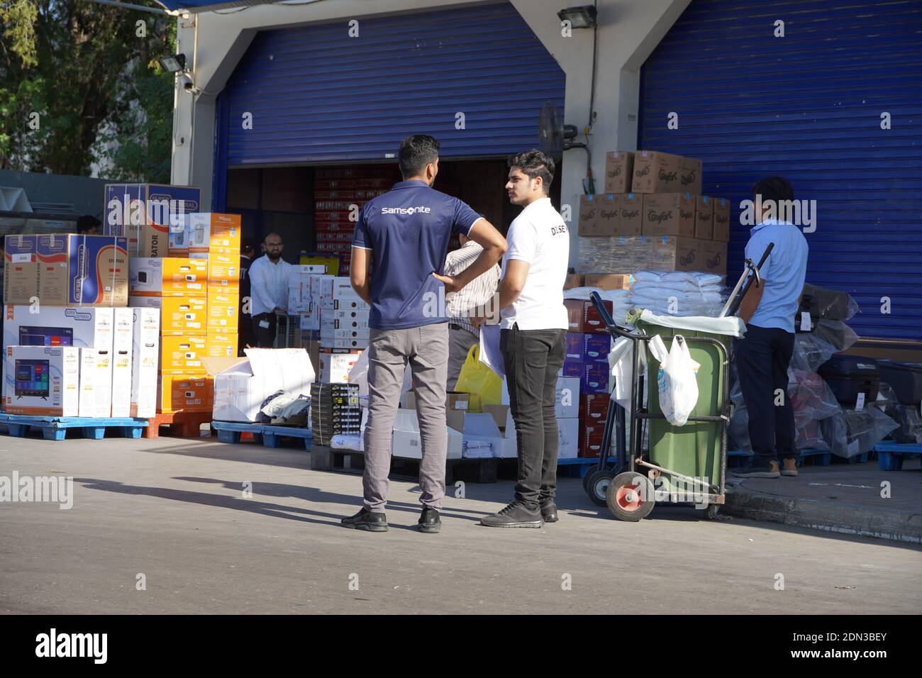 Arbeiter mit Handstapler und Kartons lagern Waren in der Nähe von Lagerräumen im Großhandel. Rückseite des Supermarktes. Entladedock für Waren am Stor Stockfoto