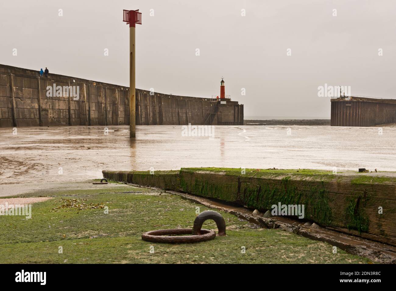 Blick von der Bootsrampe über Watchet Harbour, Somerset, England, Großbritannien bei Ebbe, mit Blick auf die Wellenbrecher und den Leuchtturm. Stockfoto