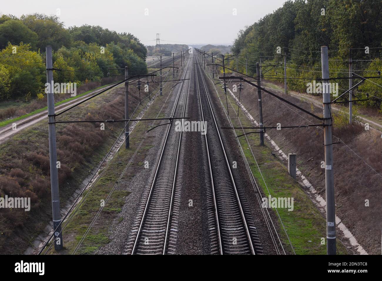 Eisenbahn, Blick von oben. Die Schienen gehen in die Ferne über den Horizont hinaus. Zwei Eisenbahnpaare fahren gerade. Stockfoto