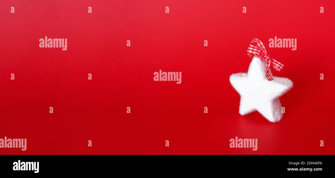 Weihnachtsbanner mit flauschiger weißer Sterndeko auf rotem Hintergrund. Winterurlaub Ornamente. Minimalistische Komposition. Stockfoto