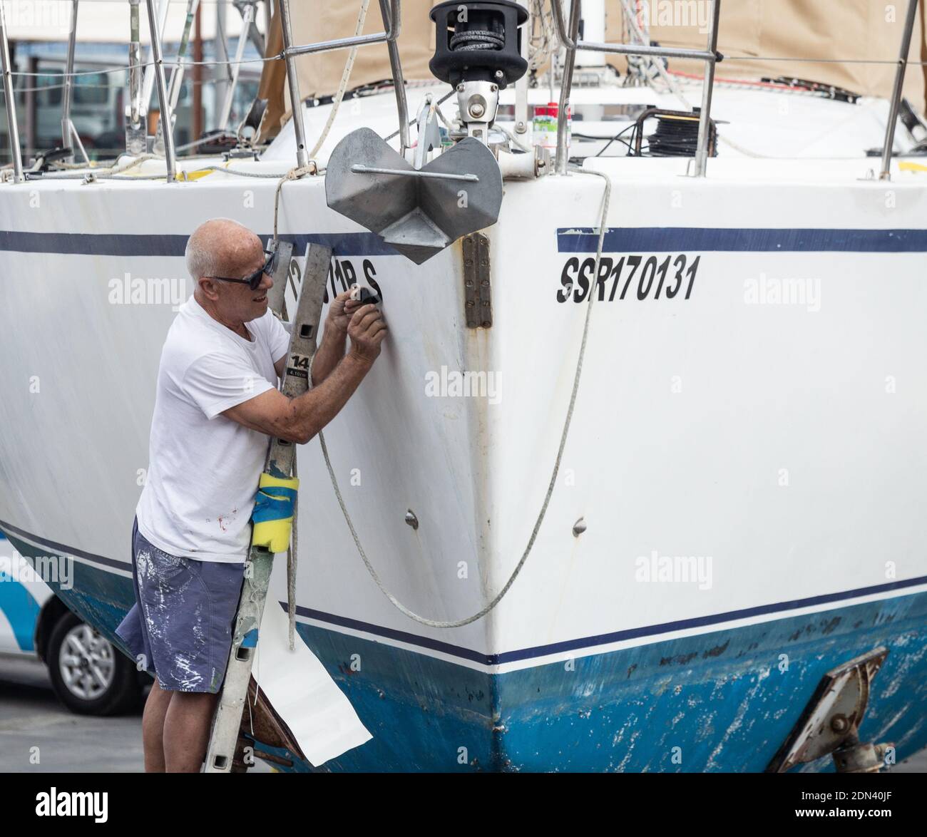 Mann, der Registrationsnummern auf der Yacht im Bootshof einlegt. Stockfoto
