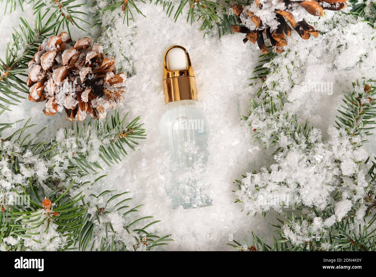 Winter kosmetisches Öl auf weißem Schnee mit weihnachtsbaum, flaches Lay, Kopierraum. Winter Hautpflege Stockfoto