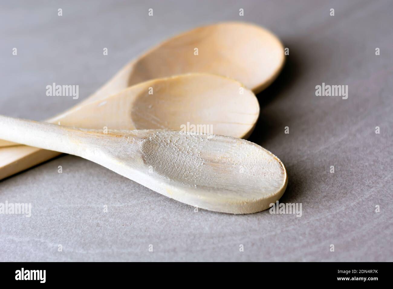 Gruppe von hölzernen Küchenlöffeln auf einem grauen Marmortisch angeordnet. Küchenutensilien und Kochen. Holzwerkstoff Stockfoto