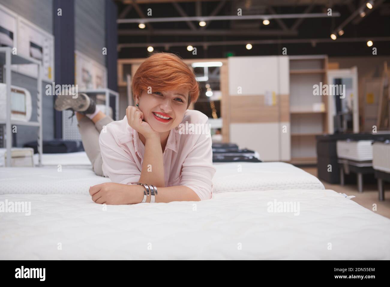 Charmante junge Frau entspannend liegend auf neue orthopädische Bett bei Möbel Supermarkt, kopieren Raum Stockfoto
