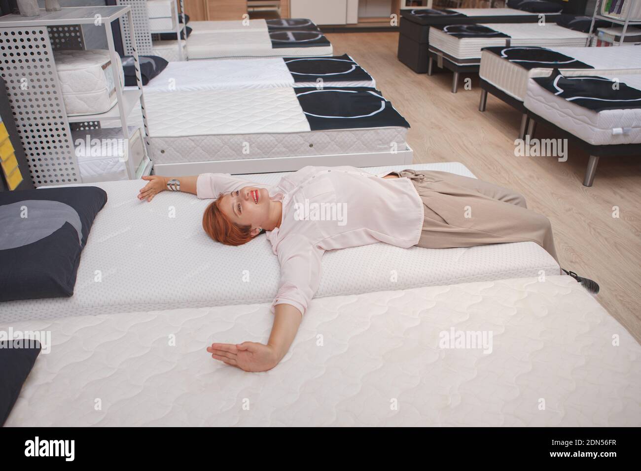 Glückliche Kundin Stretching, genießen auf orthopädischen Bett zu Hause Waren zu speichern liegen Stockfoto