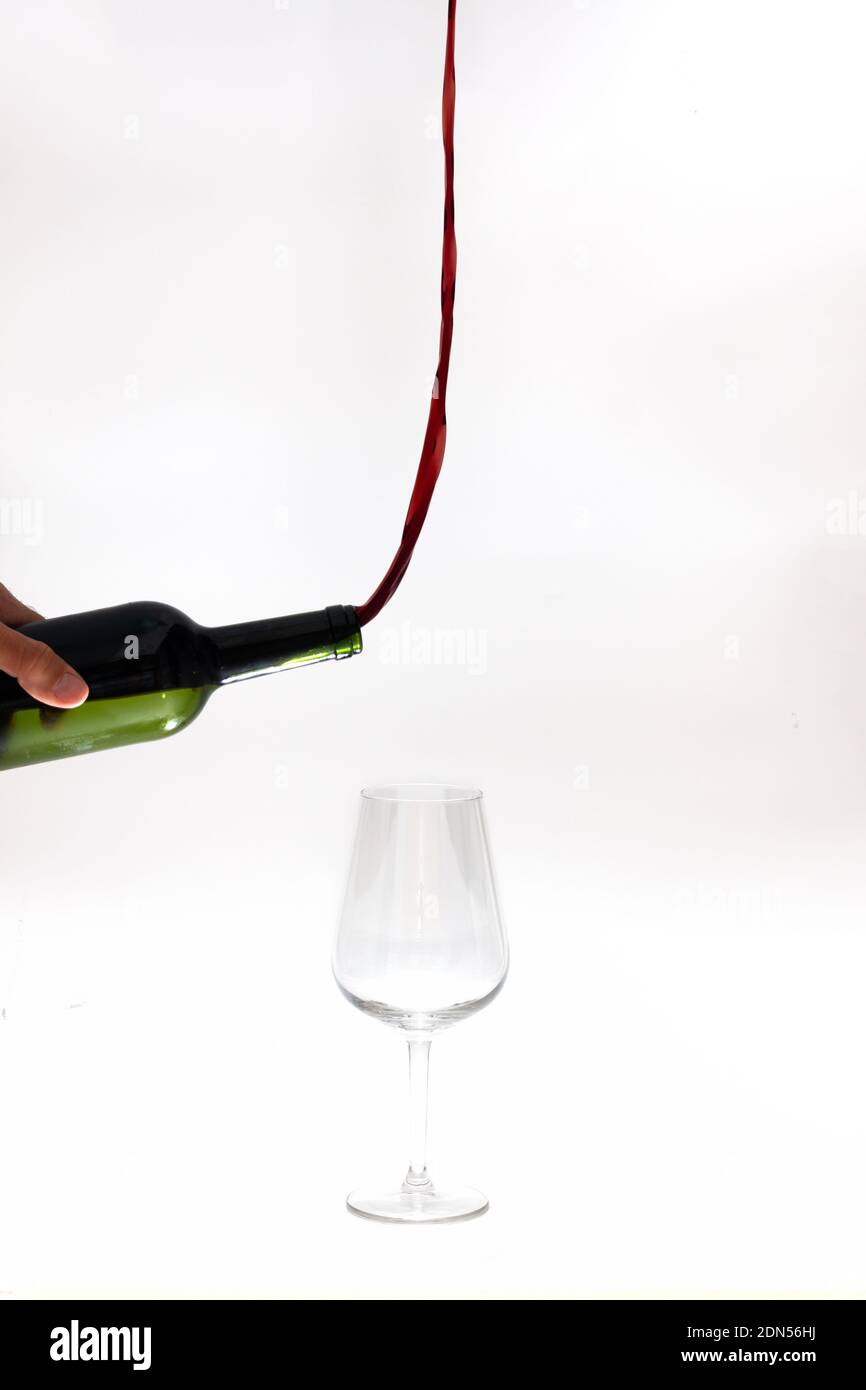 Surreales Bild von Rotwein Gießen aus einer Flasche nach oben statt des Glases auf weißem Hintergrund. Abstinenz-Konzept Stockfoto