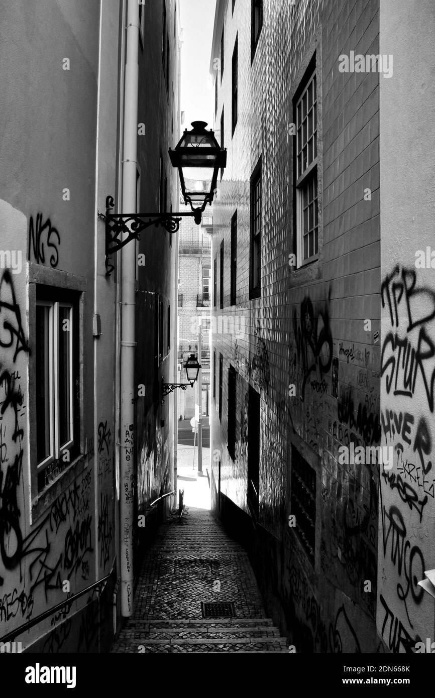 Lissabon, Portugal- 4. Dezember 2020:schmale Straße mit gefliesten Fassaden und Vintage Laternen in Lissabon, Portugal. Monochromes Bild Stockfoto