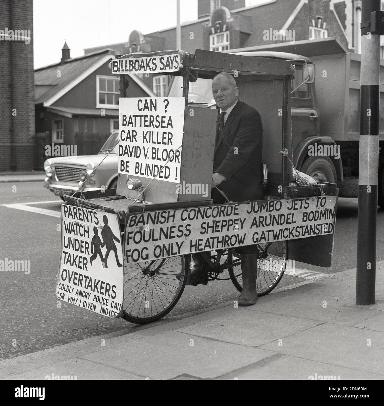 1960er, historischer, eifriger und exzentrischer Straßensicherheitskämpfer, ehemaliger Marinekommandeur Bill Boaks, der auf seinem berühmten Fahrrad mit Protestplakaten saß, neben einer belebten Straße in South London, England. UK. Commander Bill Boakes DSC Naval Hero and Cyclist - eine Inspiration für den schreienden Lord Sutch Gründer der Offiziellen Monster Raving Loony Party - stand 30 Jahre lang bei den Parlamentswahlen als Kandidat, zunächst in einem Zug, Boote und Flugzeuge und später auf der Strassensicherheit, die als demokratischer monarchistischer weißer Residenz für öffentliche Sicherheit kämpfte. Stockfoto