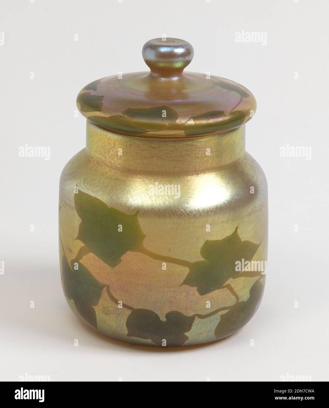 Lidded Jar, Tiffany & Company, amerikanisch, gegründet 1853, Glas, Glas (A), zylindrisch geformt, Squat, mit kurzem breiten Hals. Irrierendes Gold. Dekoration von flachen Formen von grünen Efeu Blätter durch Stiele verbunden. Passender Deckel (b), geklopft, ca. 1900, Glaswaren, Dekorative Kunst, Lidded Jar Stockfoto