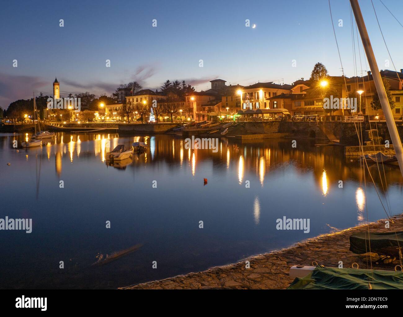 Erstaunliche Winterlandschaft mit Reflexion des beleuchteten Dorfes bei der Dämmerung an einem kalten Dezemberabend.schöne touristische Orte in der Welt, Maggiore Stockfoto